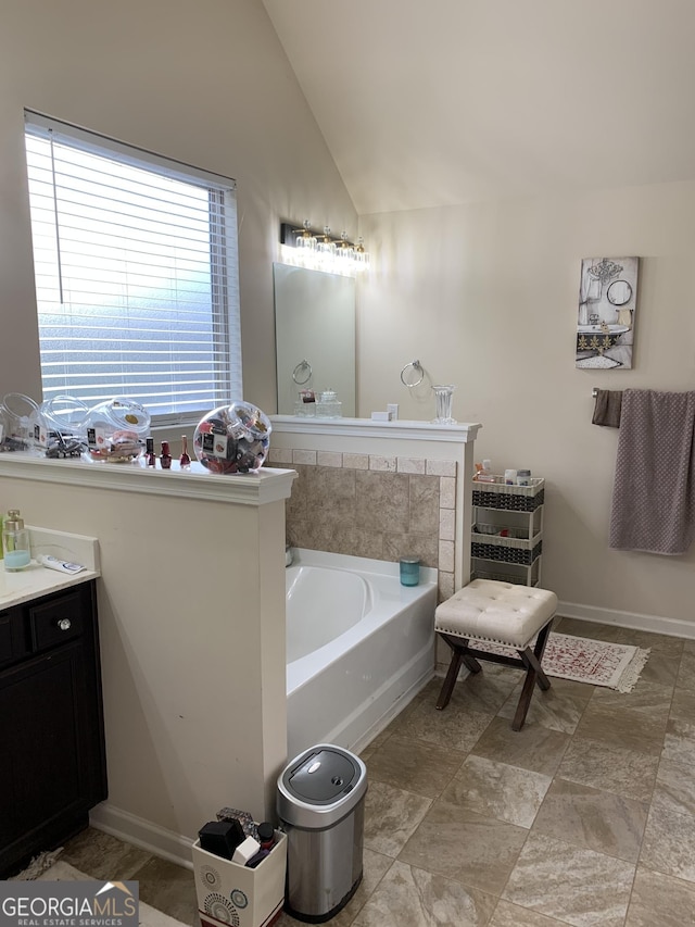 bathroom with vanity, a tub to relax in, and vaulted ceiling