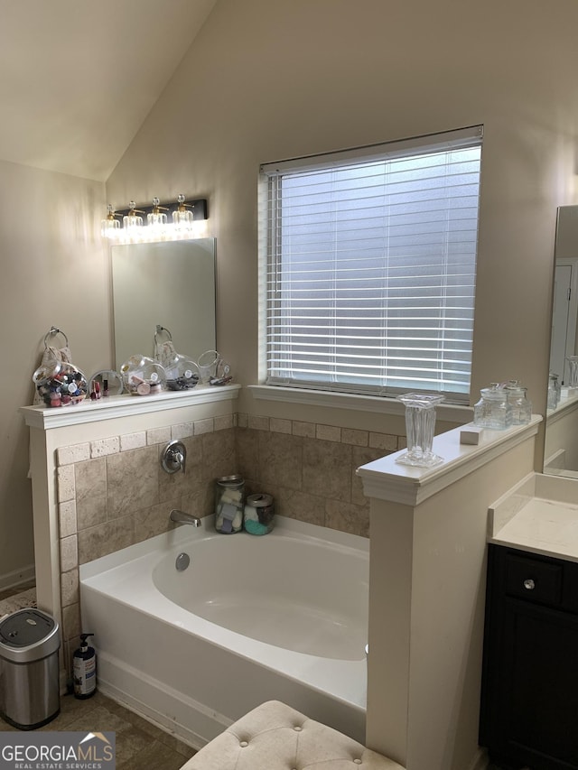 bathroom featuring a bath, vanity, and vaulted ceiling