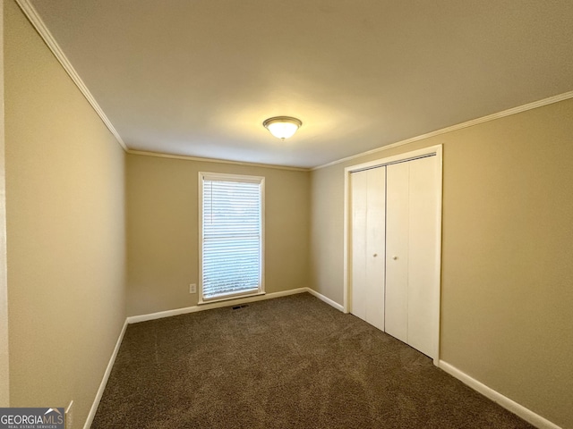 unfurnished bedroom with crown molding, a closet, and dark colored carpet