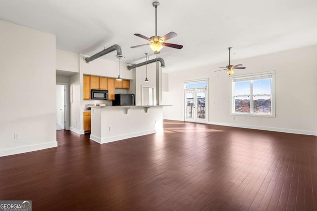 unfurnished living room featuring dark hardwood / wood-style flooring and ceiling fan