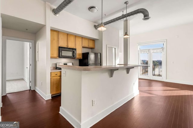 kitchen with a kitchen bar, pendant lighting, dark wood-type flooring, and black appliances