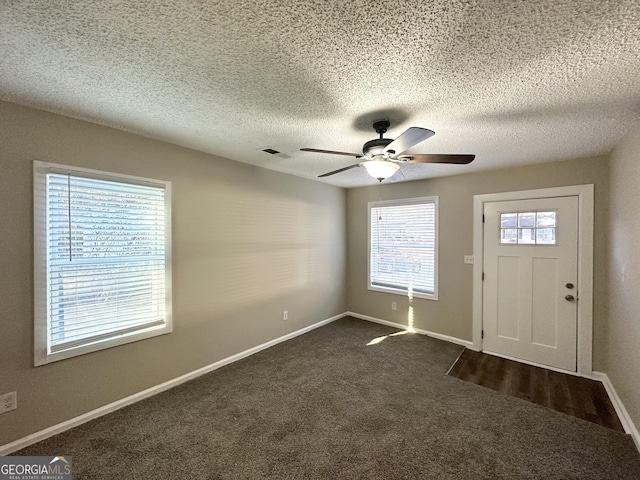 entrance foyer featuring dark colored carpet, ceiling fan, and a textured ceiling