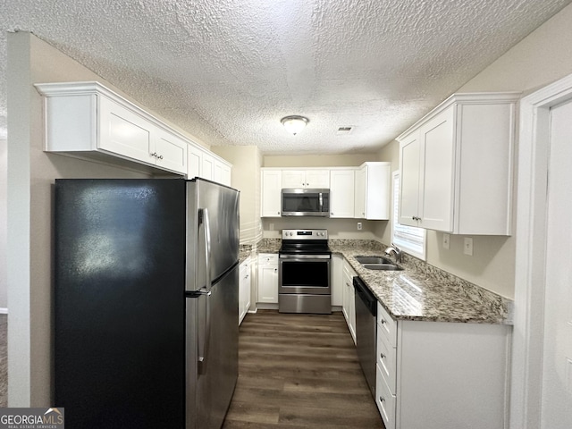 kitchen with sink, dark hardwood / wood-style floors, stone countertops, white cabinets, and appliances with stainless steel finishes