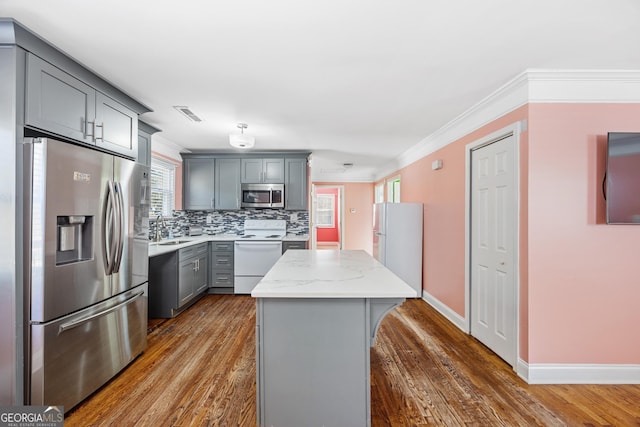 kitchen featuring backsplash, sink, gray cabinets, appliances with stainless steel finishes, and a kitchen island