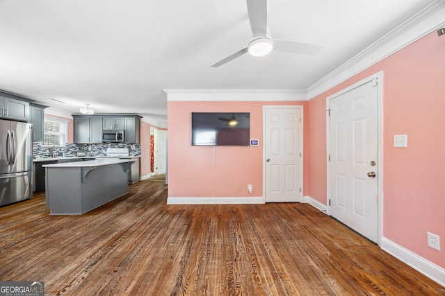 kitchen featuring gray cabinetry, stainless steel appliances, dark hardwood / wood-style flooring, a breakfast bar area, and decorative backsplash