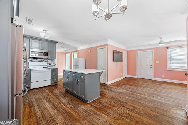 kitchen featuring stove, gray cabinetry, ceiling fan with notable chandelier, a center island, and fridge