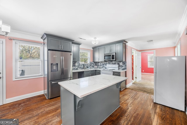 kitchen with gray cabinetry, a center island, appliances with stainless steel finishes, and tasteful backsplash