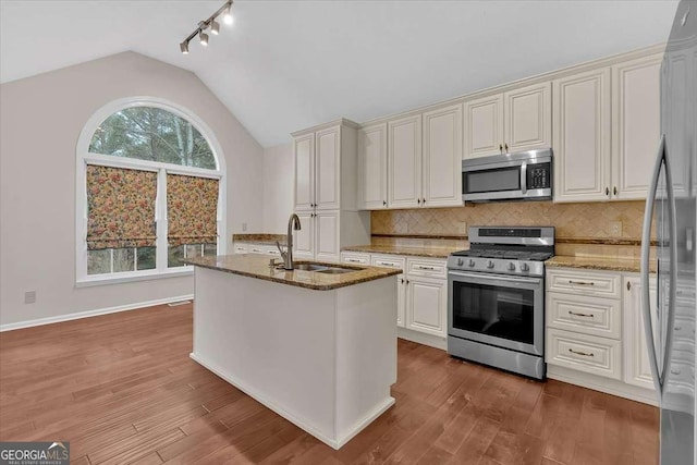 kitchen with vaulted ceiling, sink, appliances with stainless steel finishes, and dark wood-type flooring