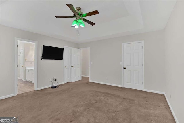 unfurnished bedroom with ensuite bathroom, ceiling fan, and light carpet