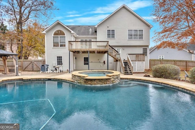 rear view of house featuring a gazebo, a pool with hot tub, and cooling unit