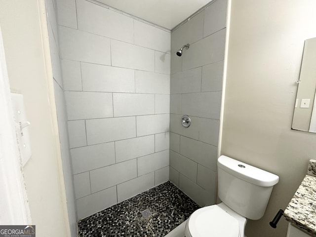 bathroom featuring vanity, toilet, and a tile shower