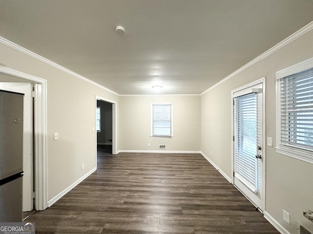 empty room with a healthy amount of sunlight, dark hardwood / wood-style floors, and ornamental molding