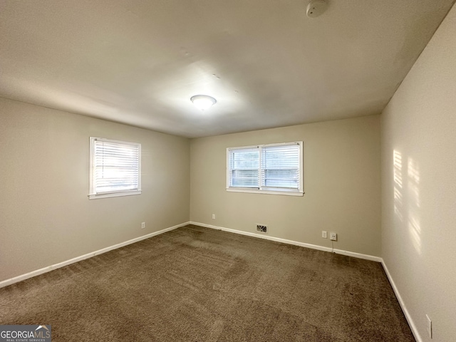 spare room with plenty of natural light and dark carpet