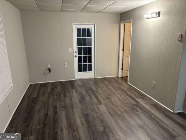 spare room featuring a paneled ceiling and dark hardwood / wood-style floors