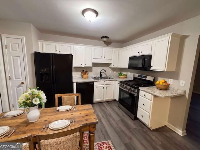 kitchen with light stone countertops, sink, dark hardwood / wood-style flooring, white cabinets, and black appliances