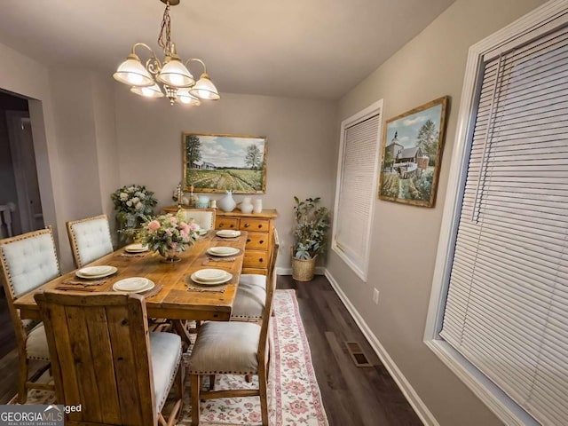 dining space with dark hardwood / wood-style flooring and an inviting chandelier