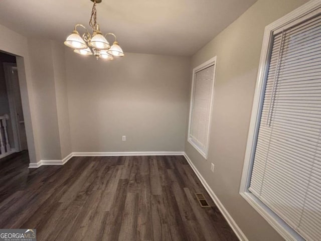 unfurnished dining area with an inviting chandelier and dark wood-type flooring