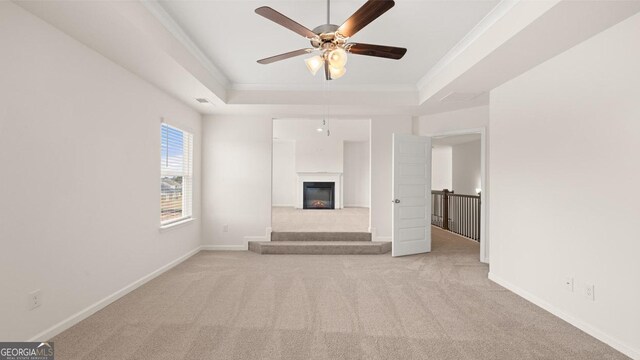 unfurnished living room featuring crown molding, light carpet, and a tray ceiling