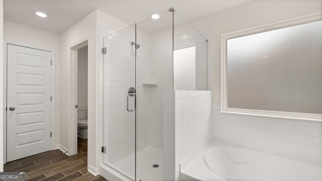 bathroom featuring shower with separate bathtub and toilet