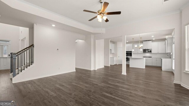 unfurnished living room with ceiling fan, sink, dark hardwood / wood-style floors, and ornamental molding