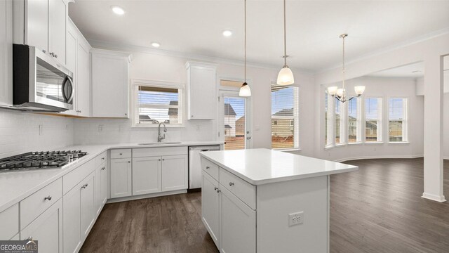 kitchen with dark wood-type flooring, appliances with stainless steel finishes, decorative light fixtures, a kitchen island, and white cabinetry