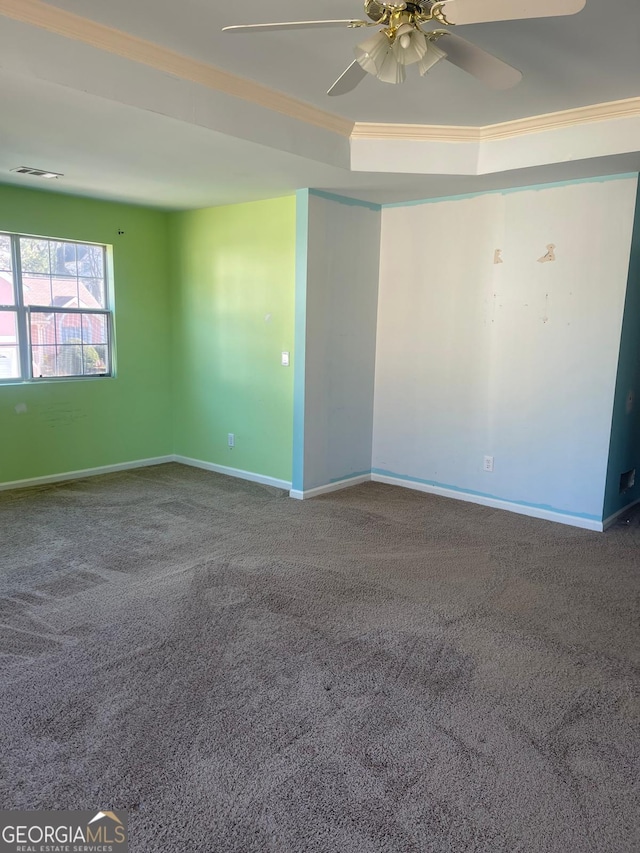 carpeted spare room with a raised ceiling, ceiling fan, and ornamental molding