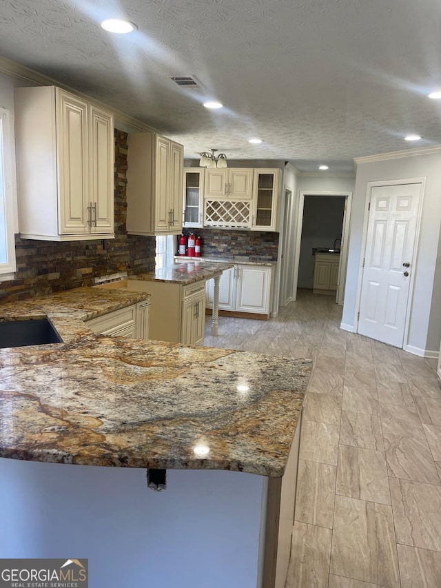 kitchen featuring cream cabinets, tasteful backsplash, crown molding, and dark stone countertops