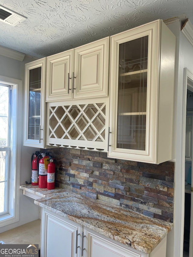 bar with light stone countertops and cream cabinets