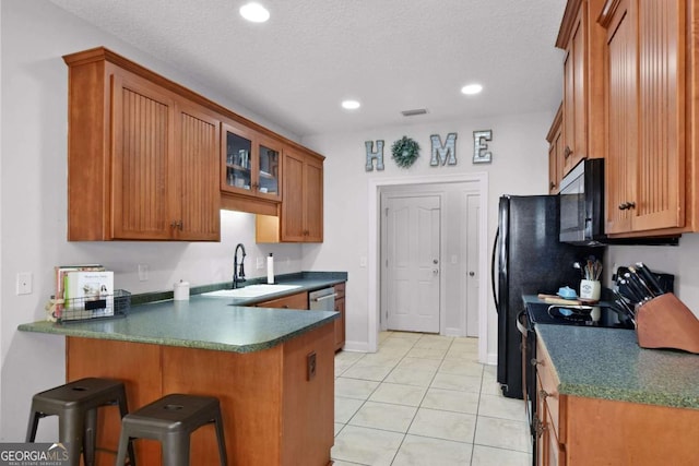 kitchen with kitchen peninsula, appliances with stainless steel finishes, a textured ceiling, and sink