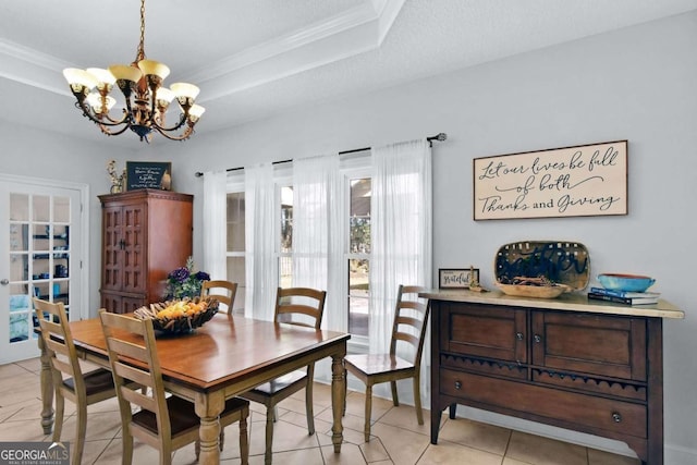 dining space with a textured ceiling, a tray ceiling, crown molding, light tile patterned floors, and an inviting chandelier