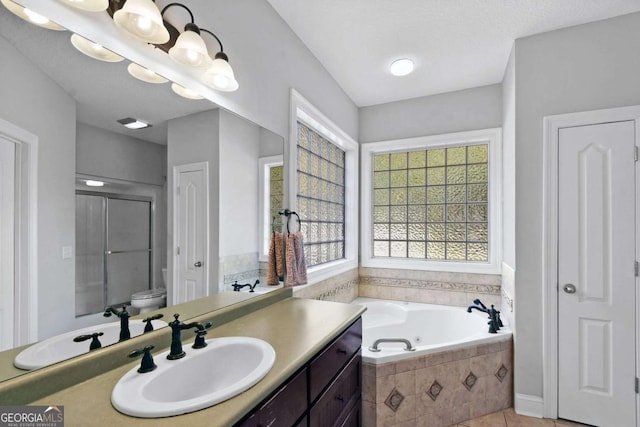 bathroom with tiled tub, tile patterned flooring, vanity, and toilet