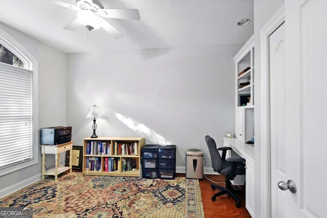 office with ceiling fan, dark wood-type flooring, and a textured ceiling