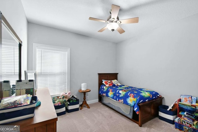 bedroom featuring ceiling fan, light carpet, and a textured ceiling