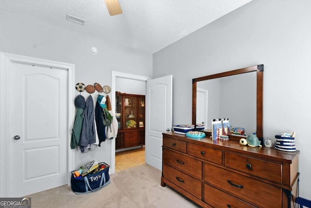 bedroom with light carpet, a textured ceiling, and ceiling fan