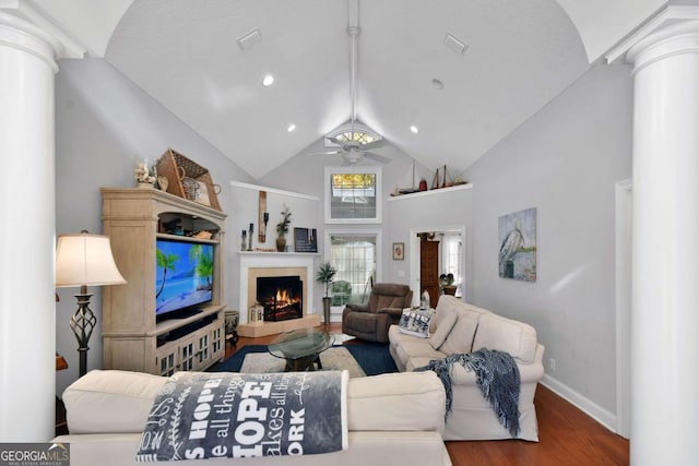 living room with wood-type flooring, decorative columns, high vaulted ceiling, and ceiling fan