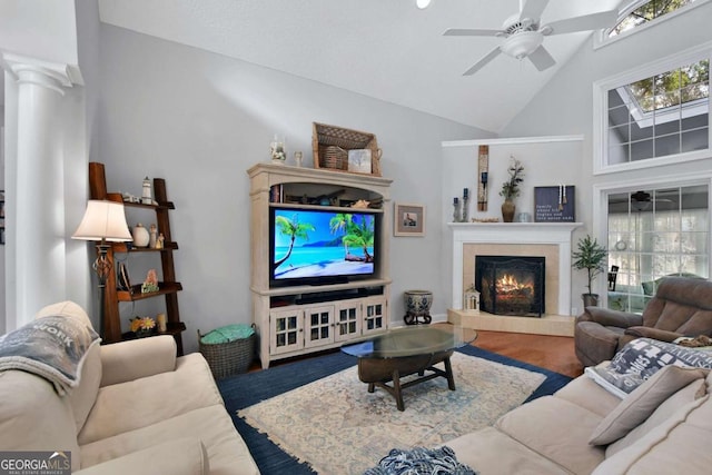 living room featuring ceiling fan, wood-type flooring, a fireplace, and high vaulted ceiling