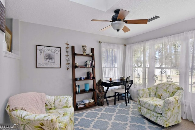 living area featuring carpet flooring, a textured ceiling, and ceiling fan