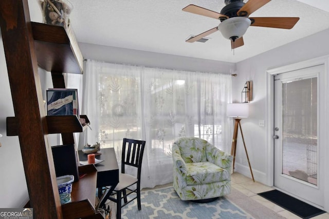 living area featuring ceiling fan, light tile patterned flooring, and a textured ceiling