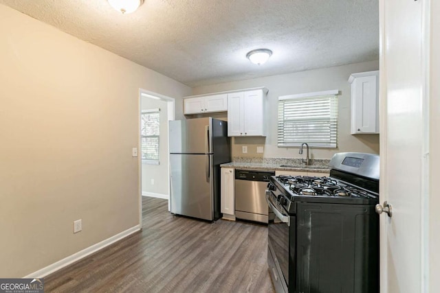 kitchen featuring light stone counters, hardwood / wood-style floors, a textured ceiling, white cabinets, and appliances with stainless steel finishes