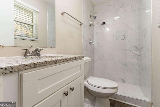 bathroom with vanity, toilet, and a tile shower