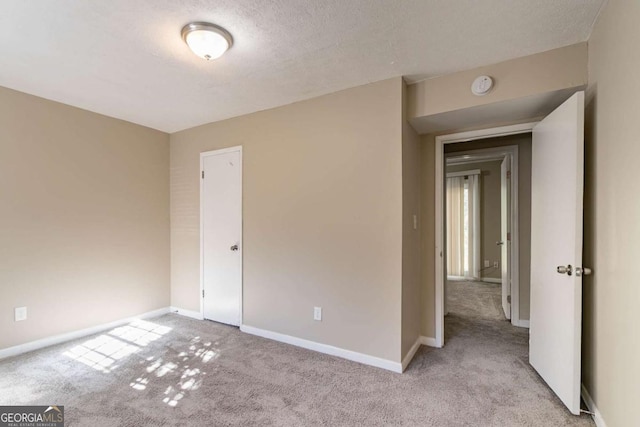 spare room with a textured ceiling and light carpet