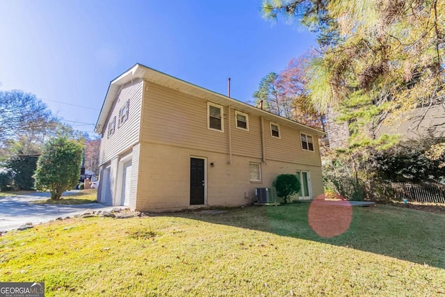 rear view of property featuring a lawn, cooling unit, and a garage