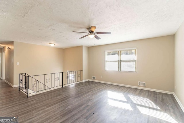 unfurnished room with a textured ceiling, dark hardwood / wood-style flooring, and ceiling fan