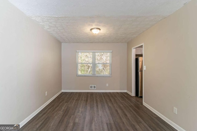 spare room with a textured ceiling and dark hardwood / wood-style floors