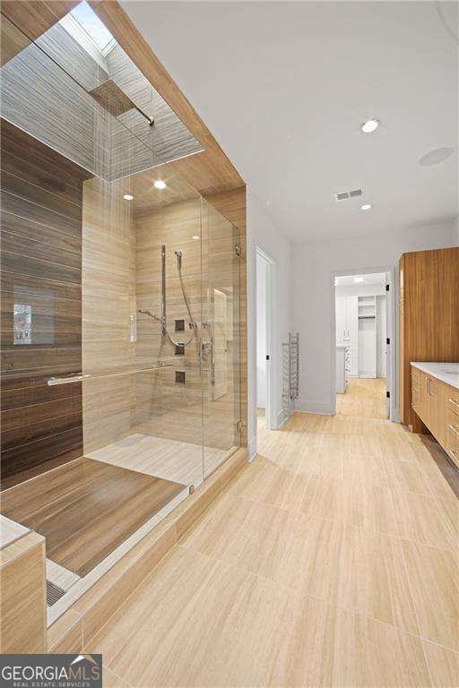 bathroom with vanity, wood walls, an enclosed shower, and a skylight