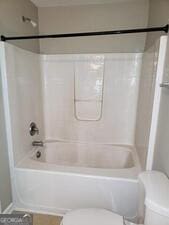 bathroom featuring shower / bathing tub combination and toilet