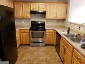 kitchen with sink, light tile patterned floors, stainless steel appliances, and light brown cabinets