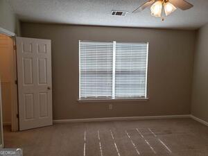 unfurnished room with ceiling fan and a textured ceiling