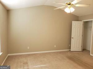 unfurnished bedroom with ceiling fan and lofted ceiling