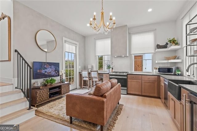 kitchen with sink, light hardwood / wood-style flooring, a notable chandelier, pendant lighting, and appliances with stainless steel finishes